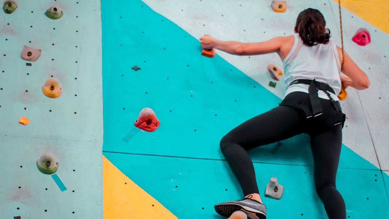 Una donna intenta ad arrampicarsi in palestra