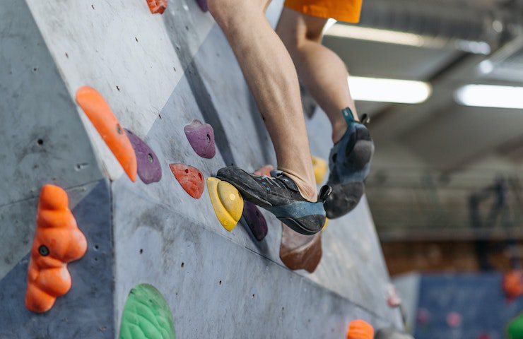 Climber che scala una parete di arrampicata sportiva