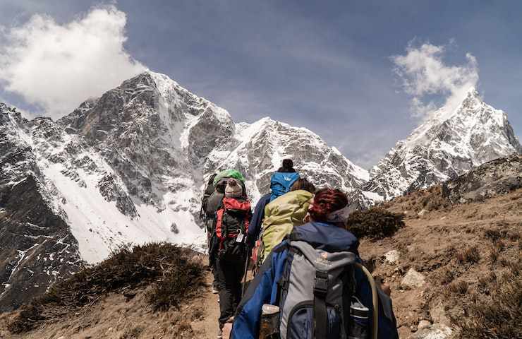 Gruppo di persone che percorre un sentiero guidato da un accompagnatore di media montagna