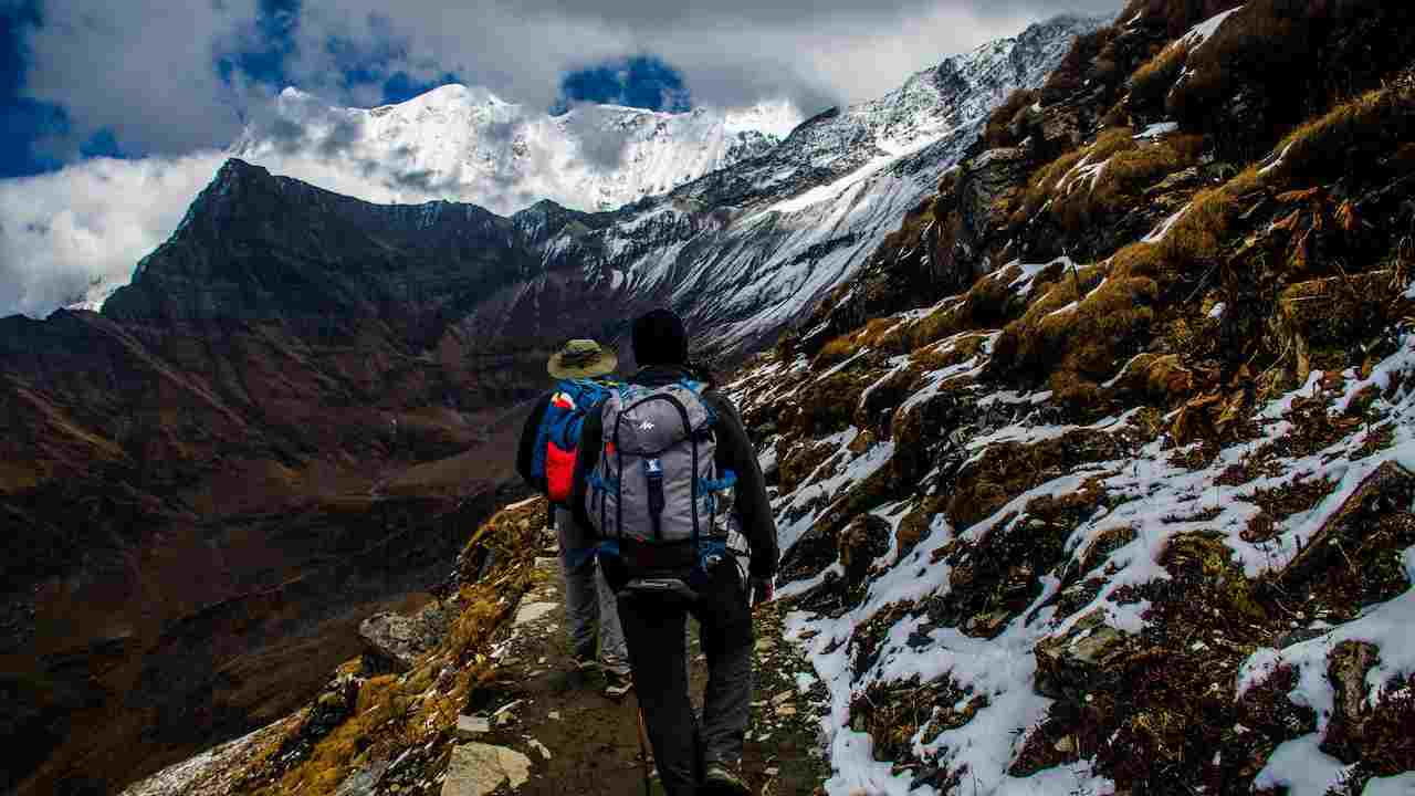 Due ragazzi che fanno trekking sulle montagne, ancora in parte innevate