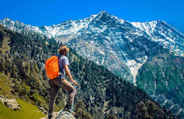 Ragazzo che fa trekking e osserva una montagna innevata