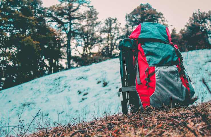 Zaino da trekking appoggiato in un campo di montagna con ancora delle neve