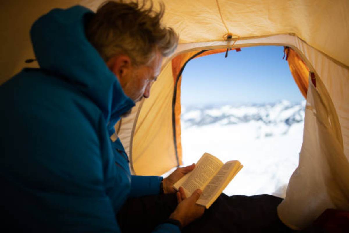 Alpinista mentre legge un libro in montagna