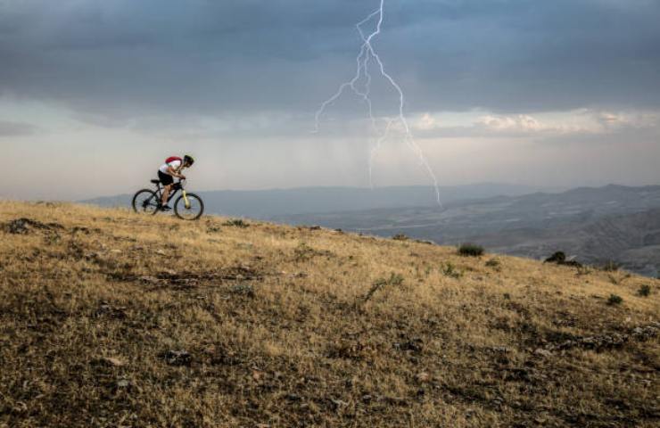 Ciclista in montagna durante un temporale con fulmini