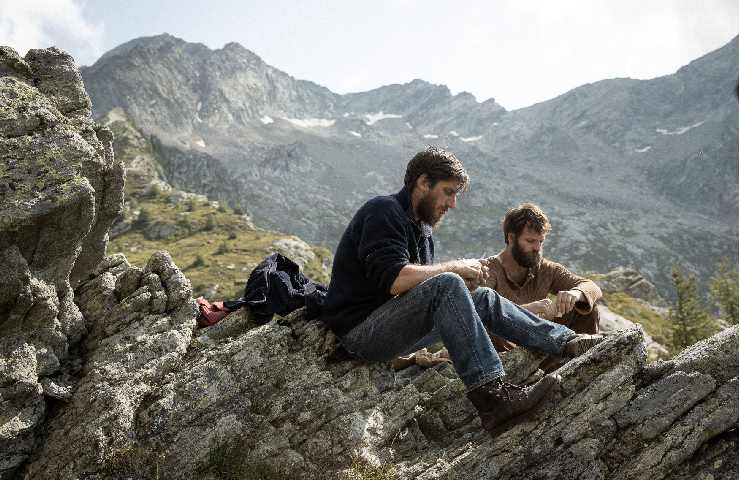 Scena da Le otto montagne in cui i due protagonisti sono a sedere su delle roccie a riflettere insieme