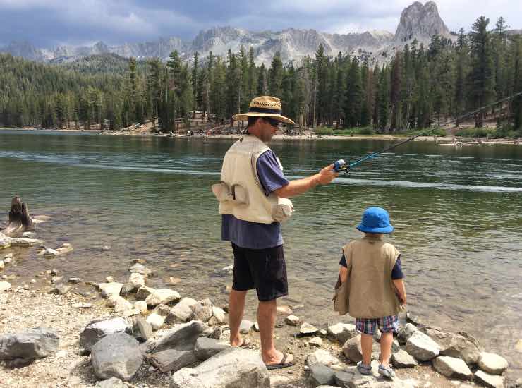 Padre e figlio pescano in un lago di montagna