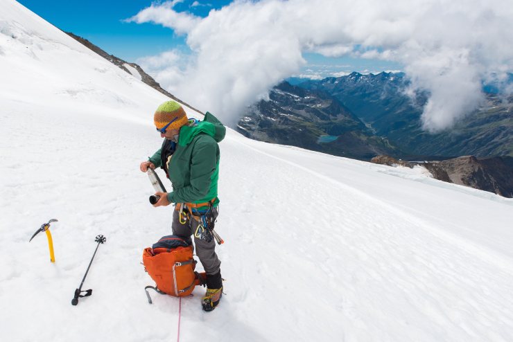 Alpinista con la sua attrezzatura sulla neve