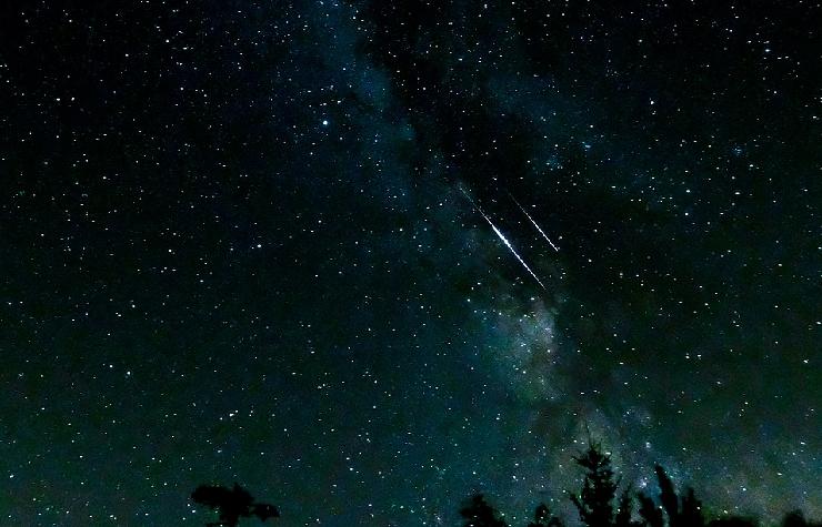 Stelle cadenti in un cielo scuro in cui si nota anche la Via Lattea