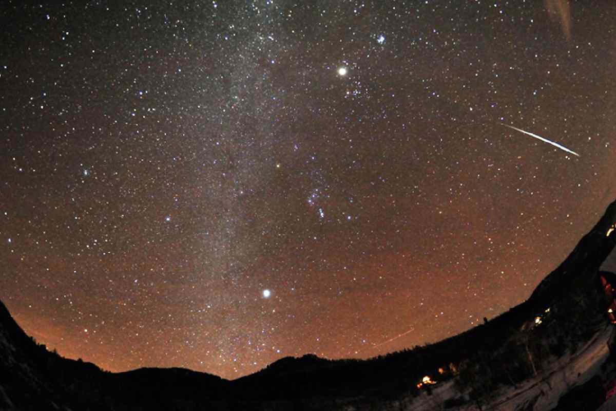 Cielo stellato montano con una luce viola sopra le vette