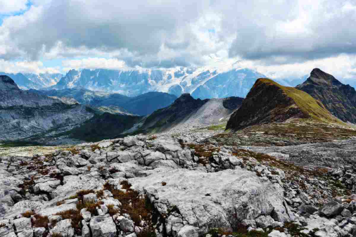 Terreno montano a chiazze di neve con nello sfondo vette più innevate