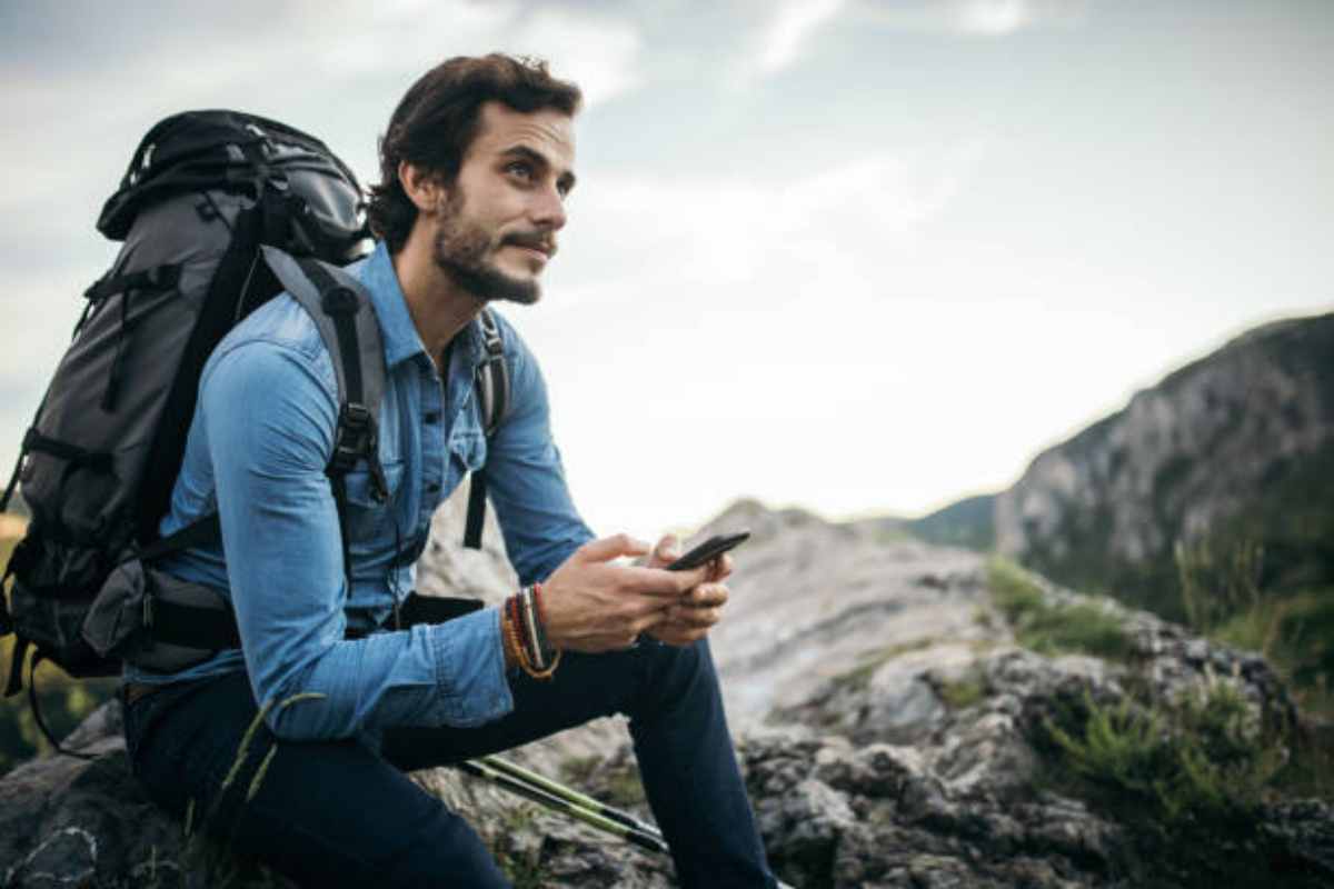 Arrampicatore utilizza delle app in montagna
