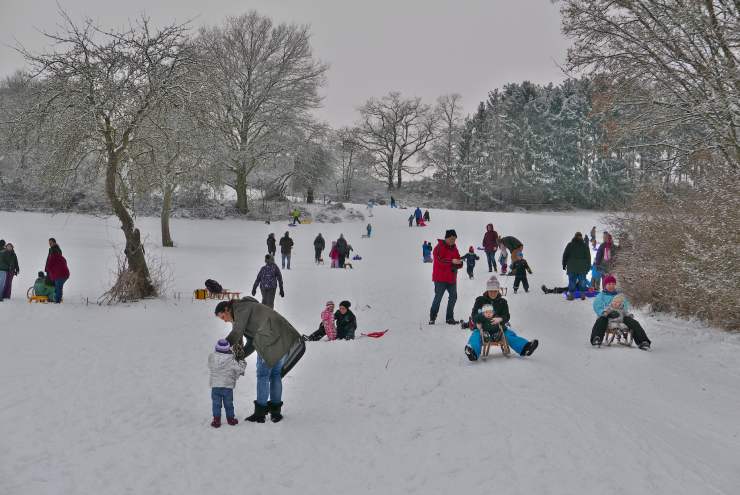 Famiglie giocano sulla neve con gli slittini