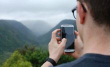 Un ragazzo intento a usare uno smartphone in montagna